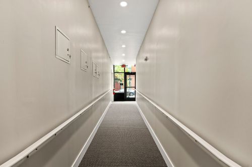 Carpeted hallway leading to a glass exterior door framed by bulletin boards