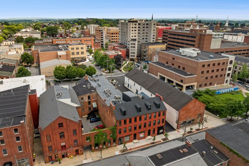 Aerial view of a renovated brick loft building near a downtown plaza and modern office tower