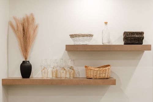 Floating wood shelves styled with glassware, a woven basket and a dried pampas arrangement