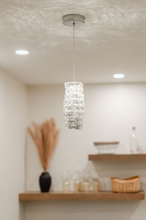 Close-up of a faceted crystal pendant light hanging from a textured ceiling