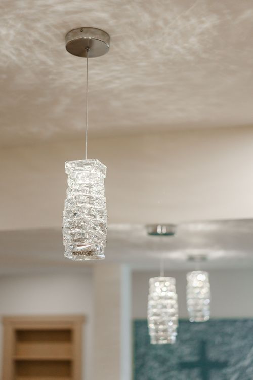 Cluster of crystal pendant lights hanging above a bar reflected in a mirrored wall