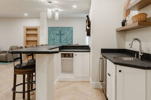 Basement wet bar with glass pendant lights, black soapstone counters and a built-in bookshelf