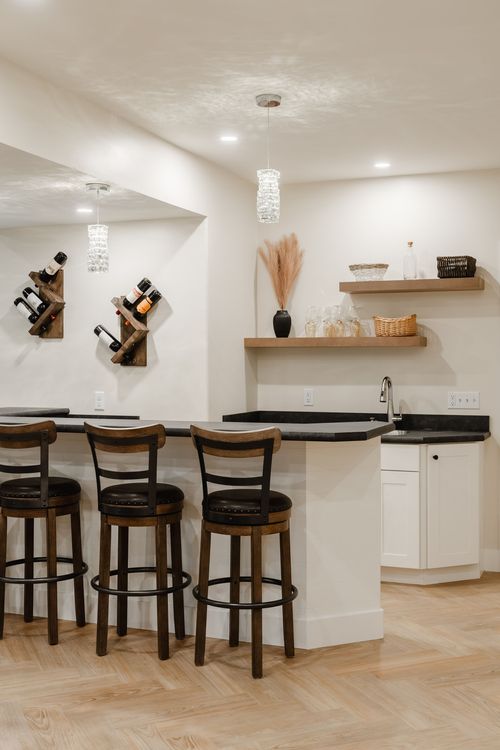 Wet bar corner with rustic wine racks, black stone countertop and cushioned barstools