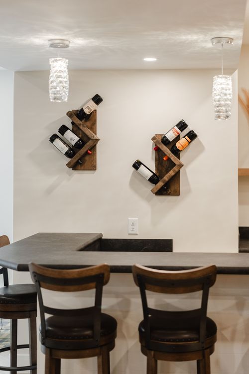Pair of rustic wood wine racks mounted on a wall above a black stone bar counter