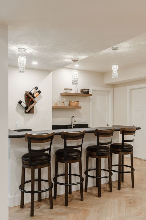 Basement bar with barstool seating, a wall wine rack and a prep sink area