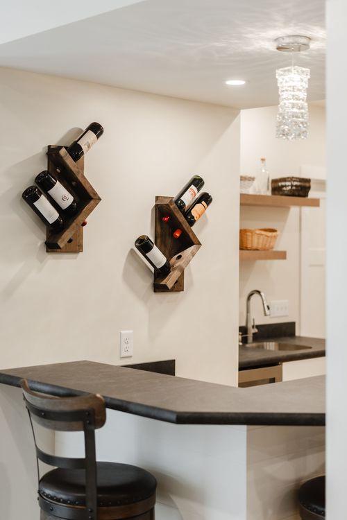 Two rustic diagonal wine racks holding bottles beneath a crystal pendant light