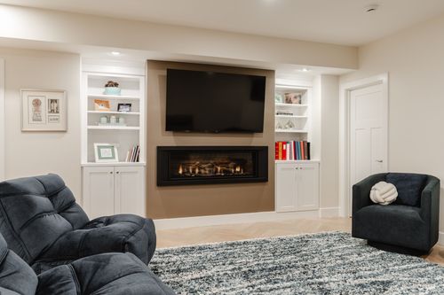 Basement family room with a modern fireplace flanked by white built-in shelving