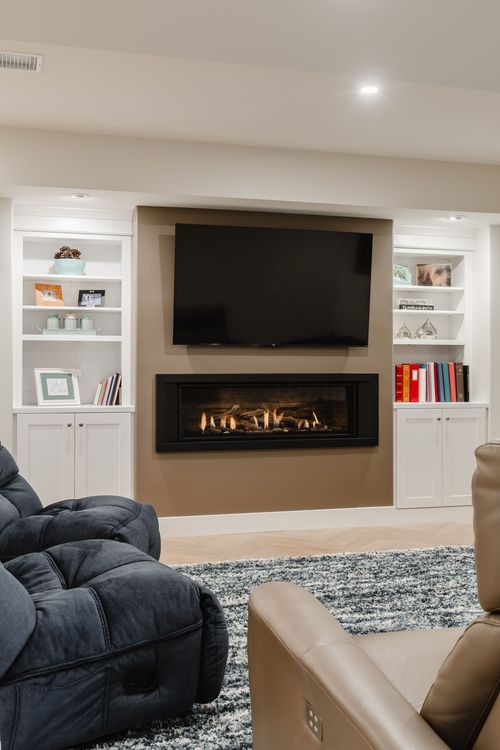 Fireplace wall with white built-in cabinetry and a leather reclining sofa in the foreground