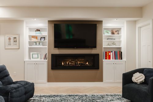 Gas fireplace flanked by white built-in shelving with books and framed photos