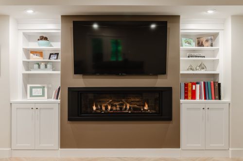Linear gas fireplace beneath a mounted TV, framed by matching built-in bookshelves