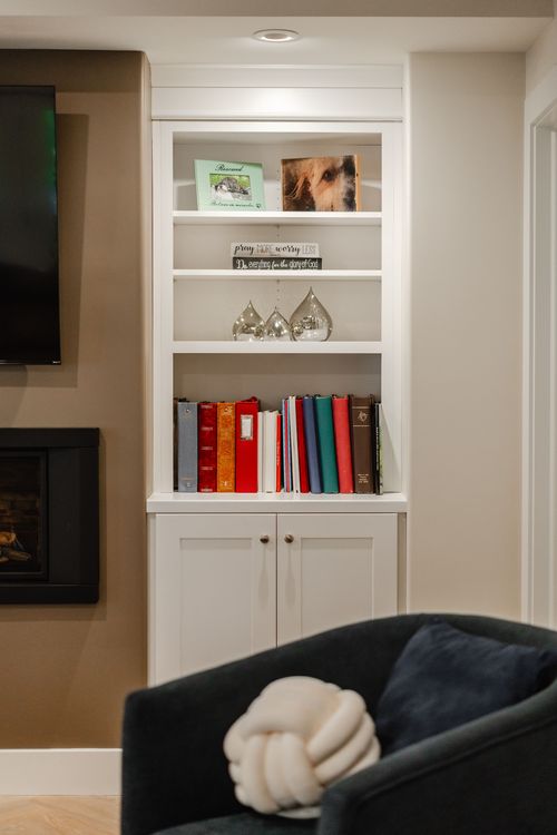 Close-up of a white built-in bookshelf styled with books, glass decor and framed photos
