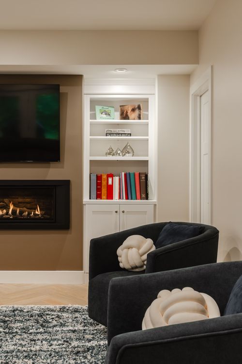 Sitting area with dark swivel chairs, a knot-textured pillow and a glowing fireplace
