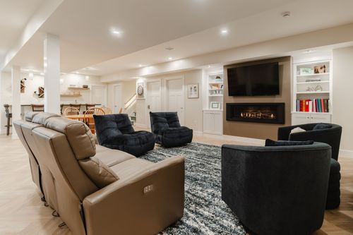 Open basement great room with a fireplace, leather sectional, dining area and staircase