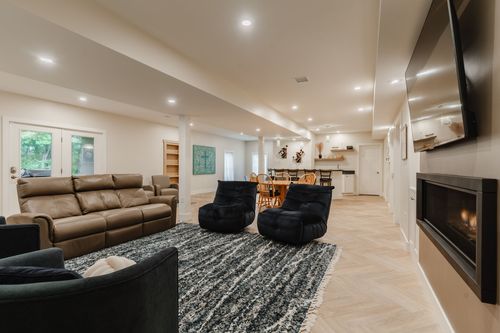 Spacious basement living area with a leather sectional, fireplace and dining space beyond