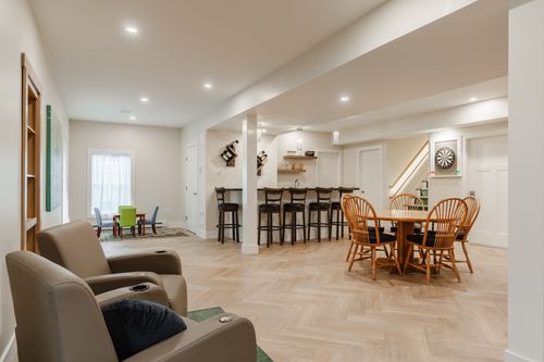 Open basement rec room with herringbone floors, a wet bar and a dining table