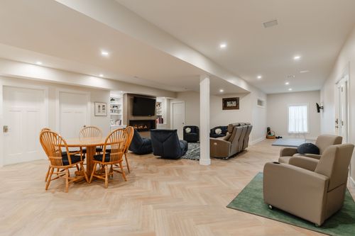 Wide view of a basement family room with a fireplace, sectional sofa and game table