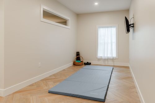 Basement flex room with an exercise mat, small transom window and wall-mounted TV