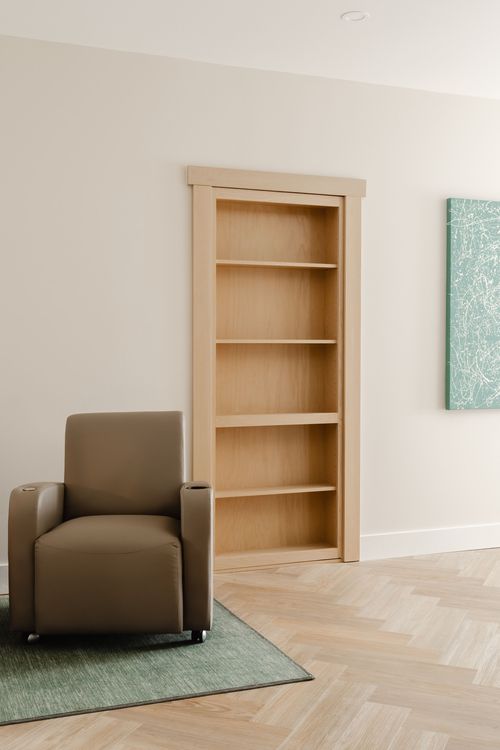 Built-in wood bookcase beside a taupe leather recliner and framed art