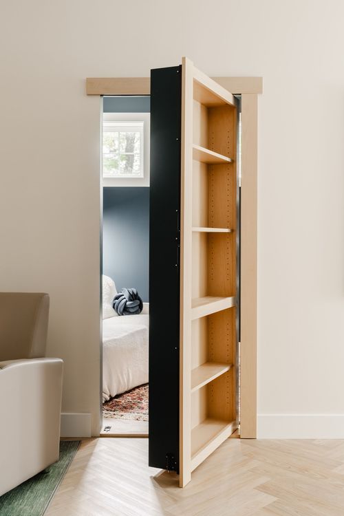 Secret bookcase door open to a bedroom with a navy accent wall