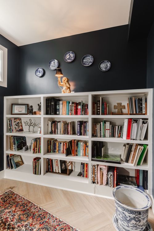 Built-in white bookshelf topped with a gilded monkey lamp and antique plates