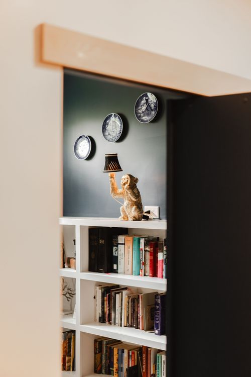 View through a doorway of a bookshelf nook with a monkey lamp and hanging plates