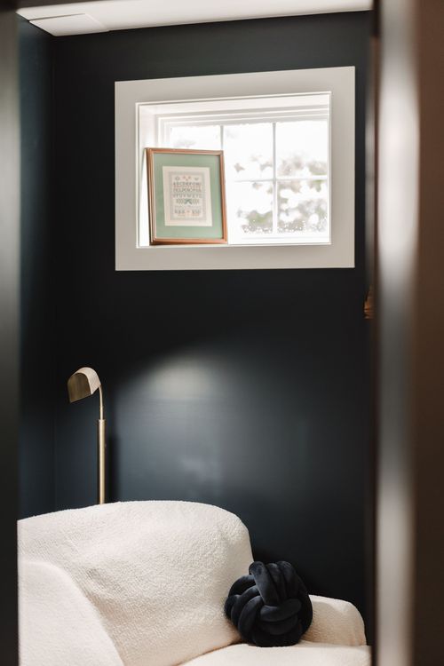 Cozy reading corner with a boucle armchair, brass sconce and framed art