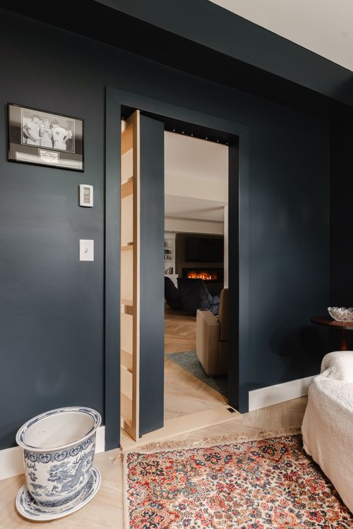 Hidden bookcase door open to a living room with a fireplace and sectional sofa