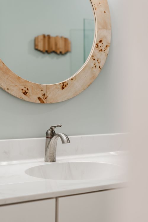 Close-up of a bathroom vanity with a burl wood mirror and brushed nickel faucet
