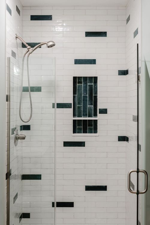 Close-up of white subway shower tile with a dark green accent tile niche