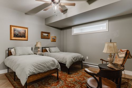 Guest bedroom with twin beds, gray walls, framed art and a patterned rug