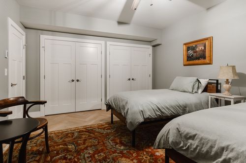 Bedroom with white shaker double closet doors and a colorful patterned rug