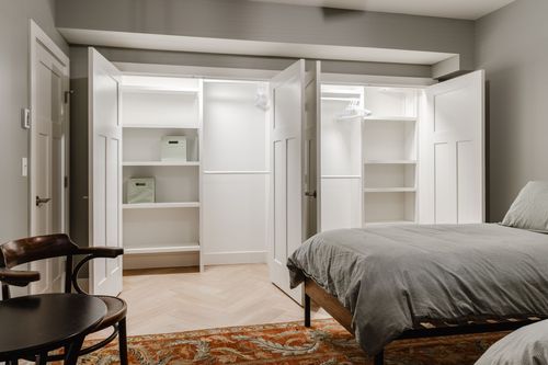 Bedroom with open closet shelving and a herringbone floor