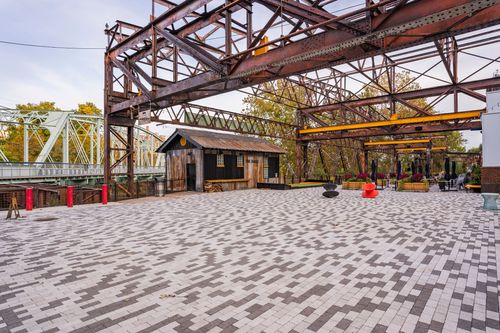 Paver courtyard with a rustic wood cabin, string lights and a steel trestle overhead