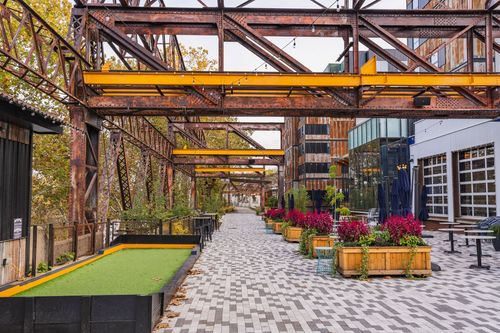 Paver walkway past a wood cabin and flower planters beneath string lights