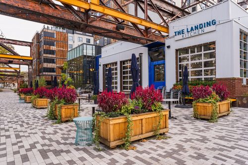Restaurant patio with wood planter boxes of red flowers and umbrellas