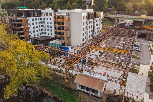 Aerial view of a hotel under construction with a steel crane structure and parking lot