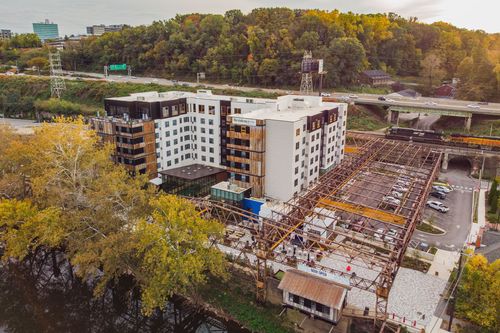 Aerial view of a hotel complex beside a river with a white truss pedestrian bridge