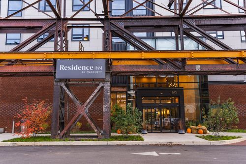 Hotel entrance beneath a steel trestle with glass doors and seasonal pumpkins