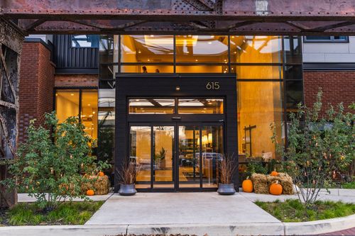 Hotel entrance with black storefront glazing, warm lighting and pumpkin displays