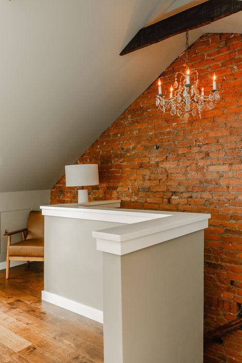Reception nook with a white built-in counter, crystal chandelier and exposed brick wall