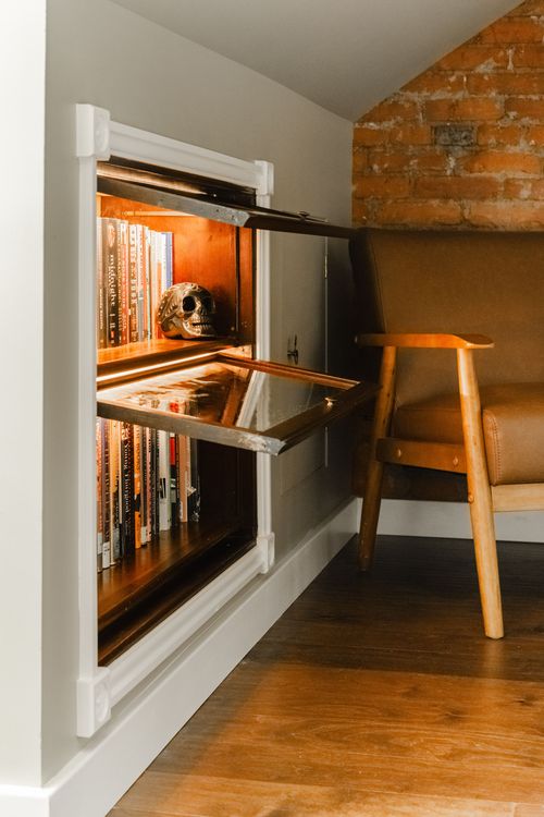 Hidden bookshelf cabinet swung open to a lit display of books