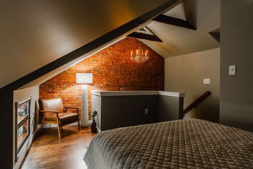Evening view of a bedroom with a small chandelier on brick and a leather armchair