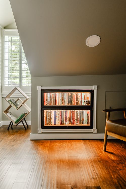 Close-up of a lit built-in bookcase beside a plantation-shuttered window