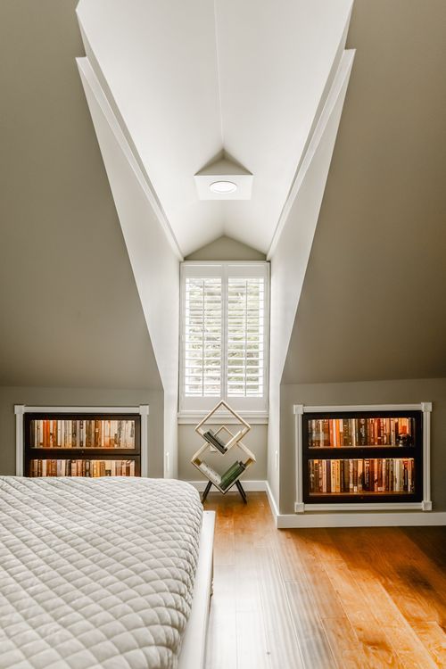 Peaked bedroom ceiling with matching lit built-in bookcases flanking a center window