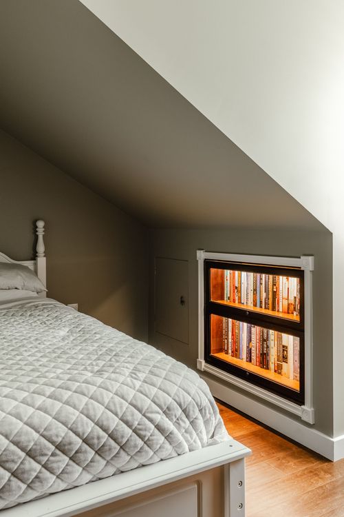 Bedroom with a white spindle bed and a single lit built-in bookcase