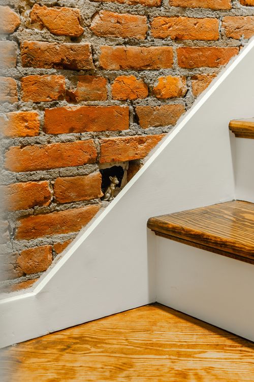 Overhead view of a wood staircase against exposed brick with a brass handrail