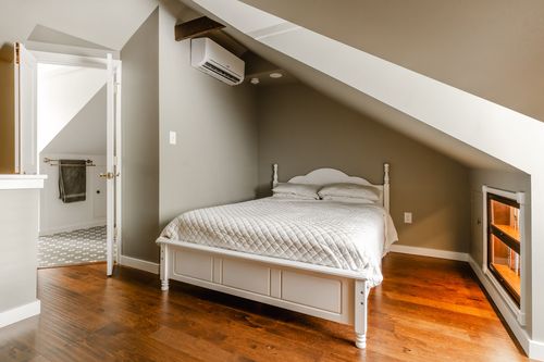 Bedroom with a white bed and an ensuite bath door open to a pedestal sink and mosaic floor