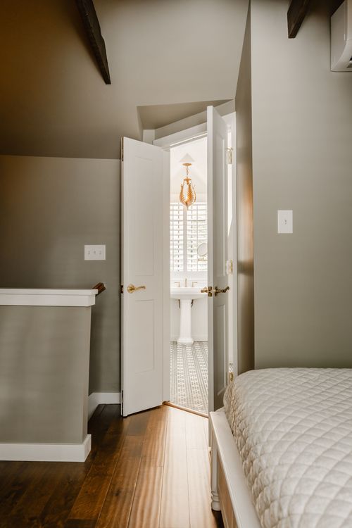 Bedroom hallway view through an open door to an ensuite bath with a pendant light