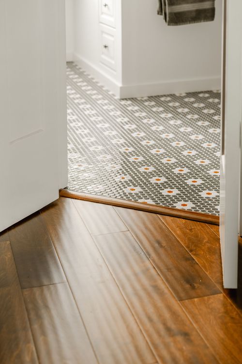 Close-up of a mosaic penny tile floor transitioning into wide-plank wood flooring
