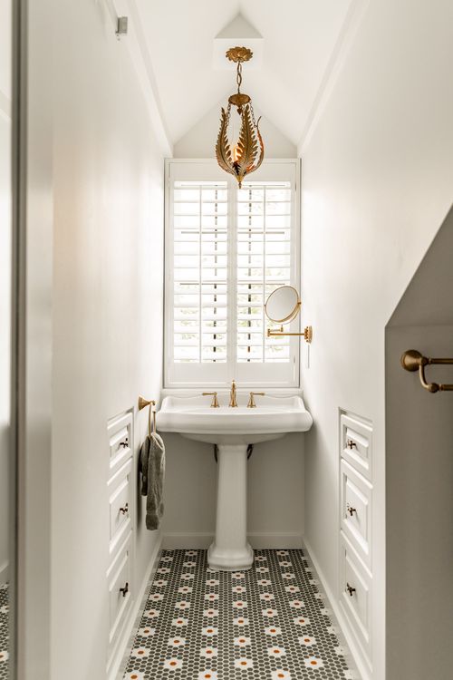 Powder room with a pedestal sink, gold leaf pendant light and plantation shutters